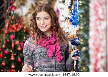 Beautiful young woman looking away while shopping at Christmas store