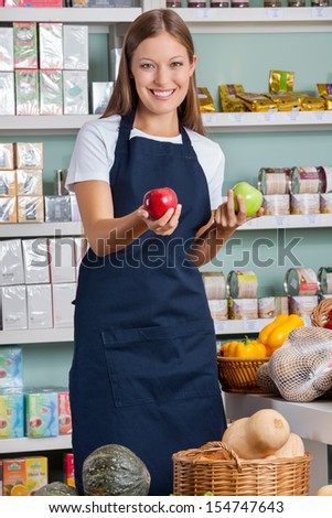 Portrait of beautiful saleswoman holding apples in supermarket