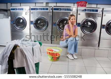 Portrait beautiful young woman using mobile phone at laundry