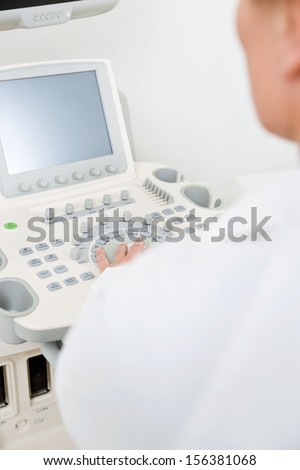 Midsection of female doctor using ultrasound machine in hospital