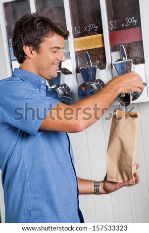 Side view of male customer buying coffee beans from vending machine at supermarket