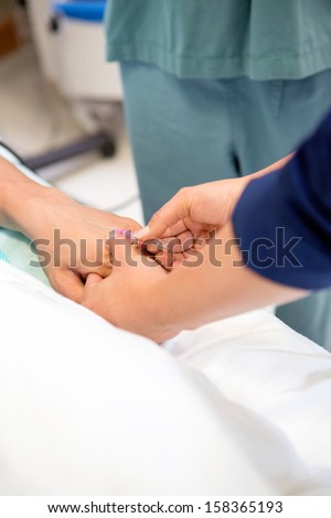 Cropped image nurse injecting needle in male patient\'s hand in hospital room