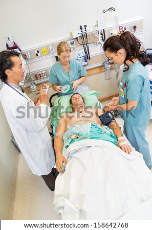 High angle view of nurses and doctor examining critical male patient in hospital