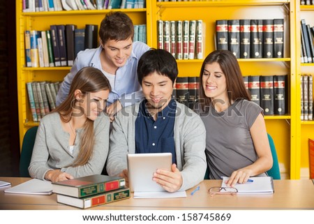 Group of multiethnic students with digital tablet studying together in college library