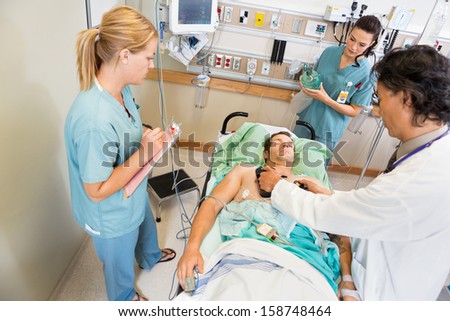 High angle view of doctor defibrillating critical patient while nurses standing by in hospital
