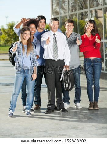 Full length portrait of confident college students and professor gesturing thumbsup on campus