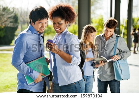 Young college students reading text message on mobilephone in campus
