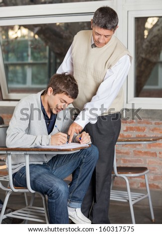 Mature male teacher explaining test to student in classroom