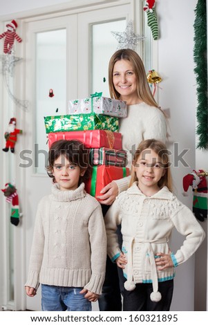 Portrait of family with gifts standing by door during Christmas at home