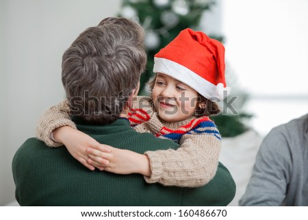 Happy son embracing father during Christmas at home