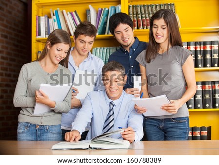 Mature university teacher with books explaining students in library