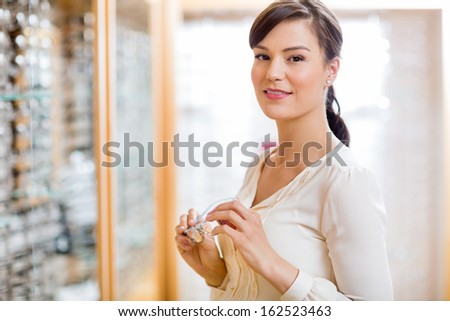 Portrait of attractive young woman holding glasses in optician store