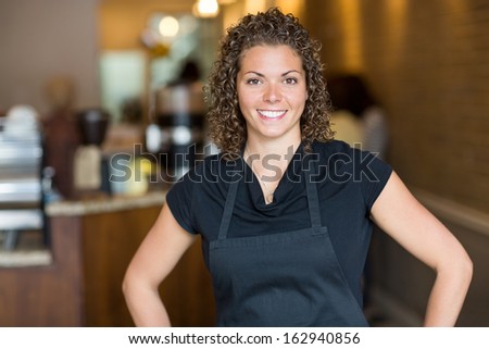 Portrait of happy mid adult waitress standing in espresso bar