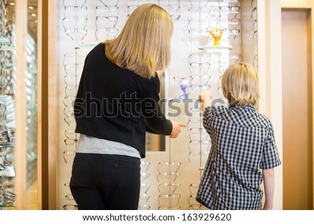 Rear view of mother and son choosing spectacles in shop