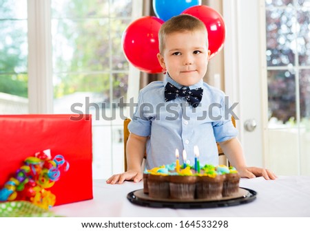 Birthday boy with cake and present on table at home