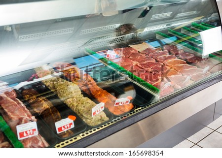 Variety of meat displayed in glass cabinet at butcher\'s shop