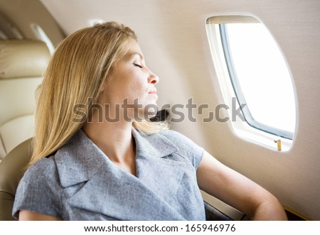 Relaxed mid adult businesswoman sleeping in private jet