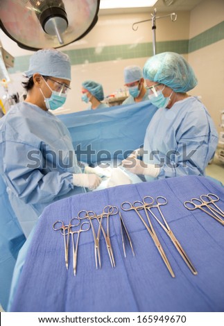 Surgical tools on stand with doctors operating patient in operation room