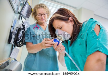 Mature female nurse woman in active labor with nitrous oxide mask.