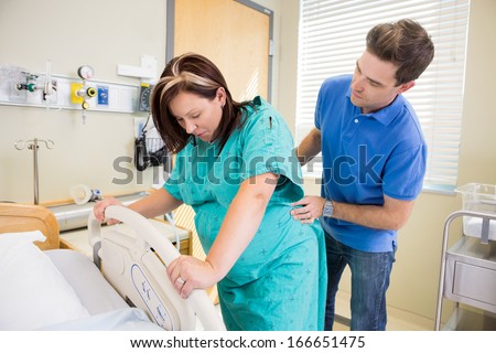 Pregnant woman undergoing a contraction during labour with husband massaging lower back