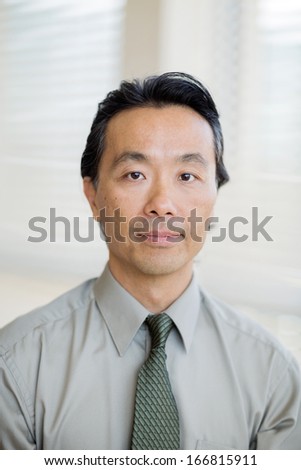 Portrait of confident Asian cancer specialist in shirt and tie at hospital