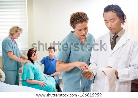 Nurse and doctor discussing fetal monitor report in maternity ward