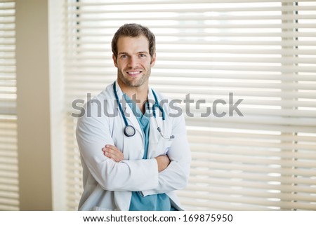 Portrait of confident male cancer specialist with arms crossed smiling at clinic