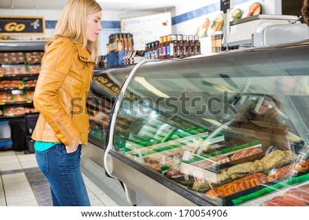 Side view of female customer selecting meat at butcher\'s shop