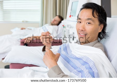 Portrait of male cancer patient eating crushed ice during dialysis at hospital room