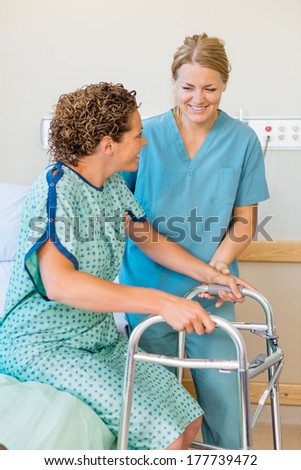 Happy mid adult nurse assisting female patient using walker in hospital