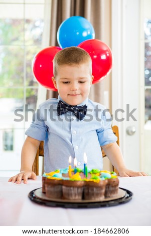 Happy boy looking at birthday cake at home