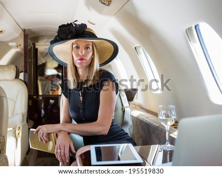 Portrait of confident rich woman sitting in private jet