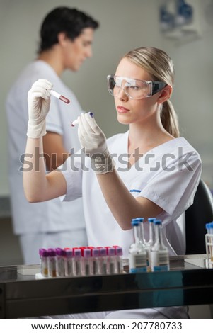 Female lab technician analyzing blood samples in test tubes