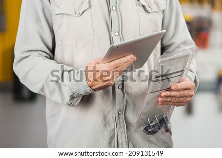 Midsection of male customer checking product through digital tablet in hardware store