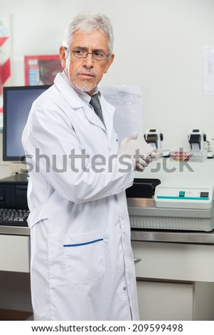 Mature male scientist standing by analyzer in medical laboratory