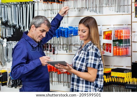 Mid adult female customer showing digital tablet to male vendor in hardware store