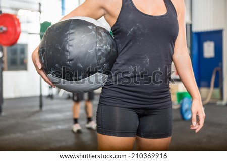 Midsection of female athlete carrying medicine ball at gym