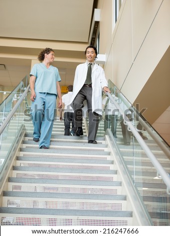 Low angle view of female nurse and doctor walking down stairs in hospital
