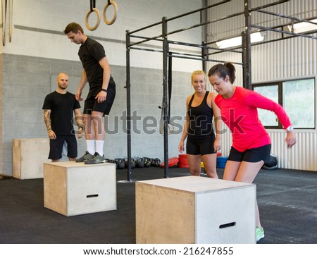 Group of male and female athletes box jumping