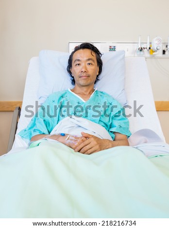 Portrait of mature male patient reclining on bed in hospital