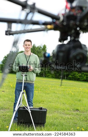 Young male engineer flying UAV octocopter with remote control in park