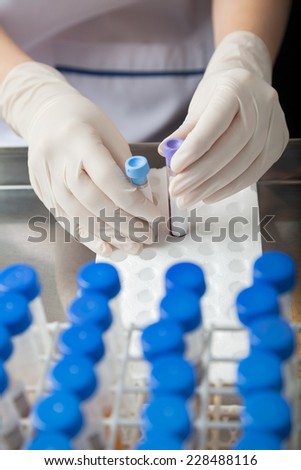 Cropped image of female lab technician placing test tube samples in tray