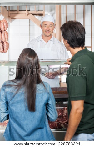 Mature couple buying meat from butcher shop