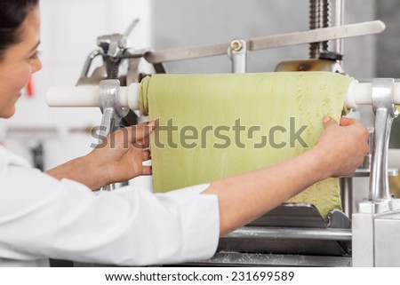 Cropped image of chef adjusting ravioli pasta sheet in machinery at commercial kitchen