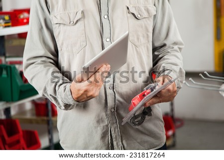 Midsection of man scanning product through digital tablet in hardware store