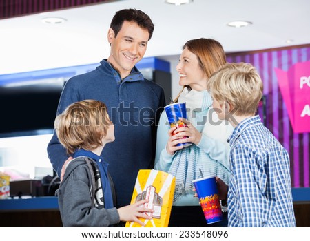 Happy family of four having snacks by cinema concession stand