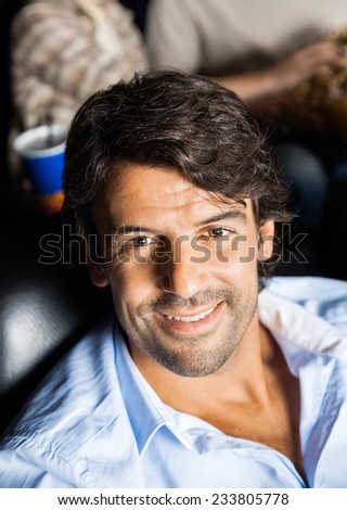 Portrait of happy man in cinema theater with family in background