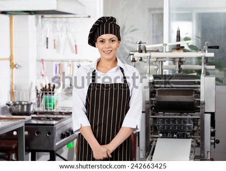 Portrait of smiling female chef standing in commercial kitchen