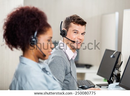 Portrait of smiling male customer service representative with female colleague working in office