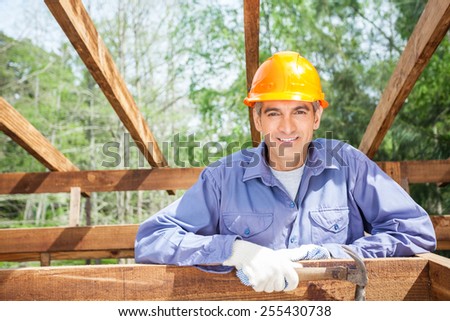 Portrait of smiling male worker holding hammer at construction site